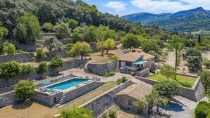 A villa with a swimming pool, stone walls, and a view of the surrounding hills. - Ca na Copea - Four Bedroom Villa, Sleeps 7 (Pollença)