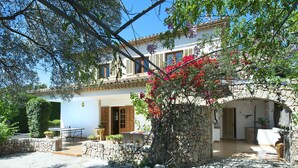 A Mediterranean-style villa with a stone archway, a patio with outdoor furniture, and a garden with flowering plants. - VILLA VOLANTI - 10 MIN WALK TO THE OLD TOWN (Pollensa)