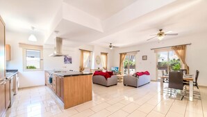 A spacious living area with a kitchen, dining table, and sofas. - Villa Alex - Charming Kapparis Getaway (Protaras)