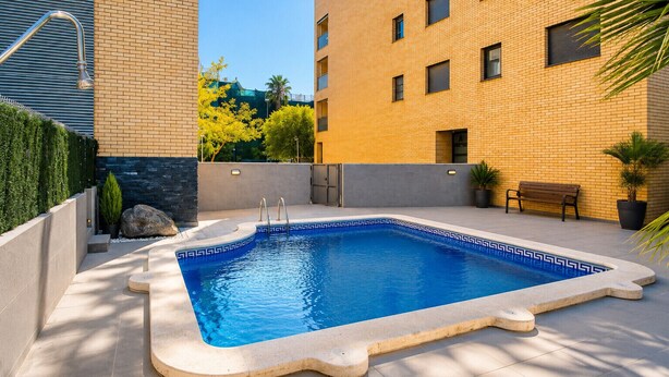 Ein rechteckiger Pool mit geometrischem Fliesendesign, umgeben von einer niedrigen Ziegelmauer und einer flachdachartigen Fläche.