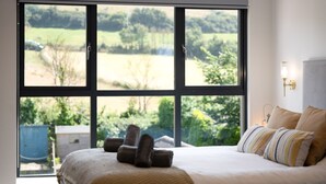 Ein Schlafzimmer mit einem großen Fenster, einem Bett mit gestreifter Decke und einer Wandlampe.