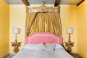 Un lit avec une tête de lit, deux tables de chevet avec des lampes et un rideau.
