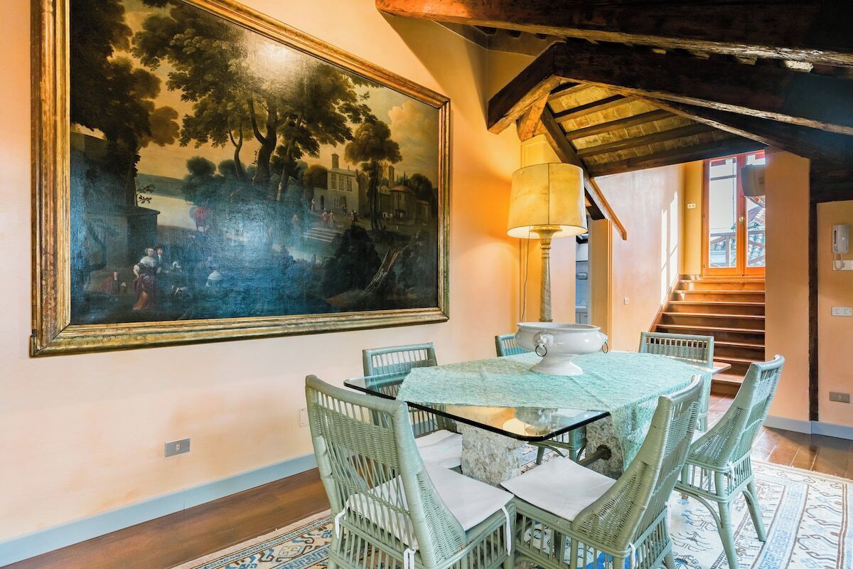 Un coin repas avec une table et des chaises, un tableau accroché au mur et un escalier menant à un autre niveau.