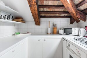 A kitchen with white cabinetry, a microwave, a coffee maker, and a brick ceiling.