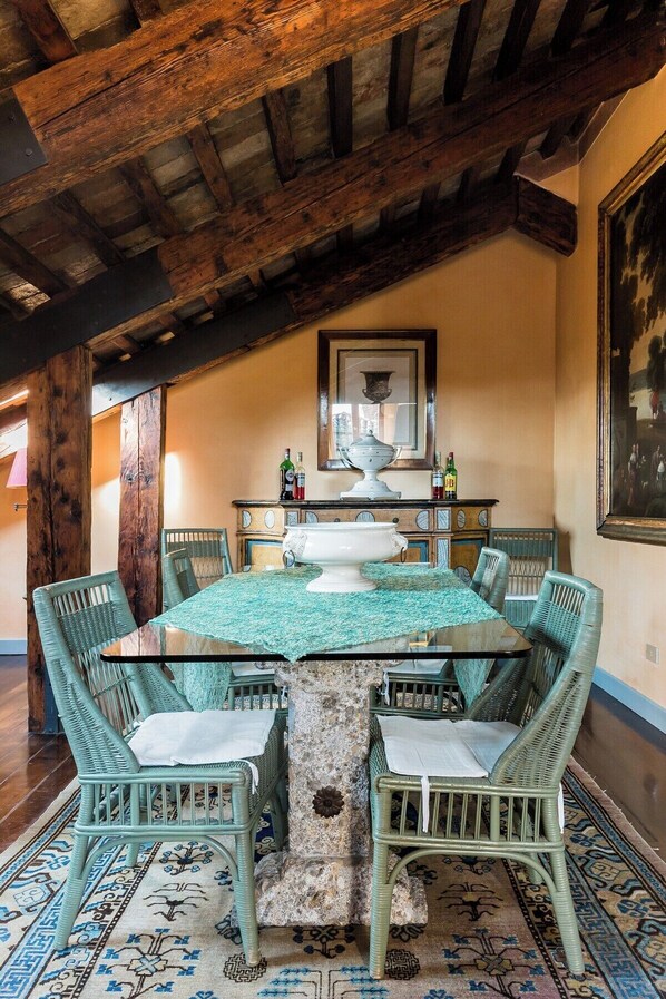A dining area with a round table, six chairs, and a stone pillar.