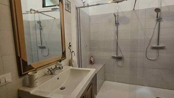 Une salle de bain avec un grand miroir, un lavabo, une douche et une fenêtre.