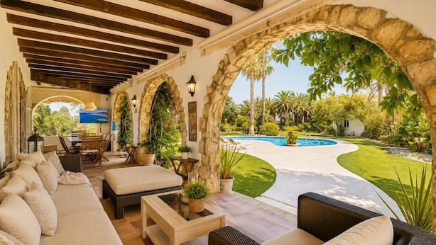 Un espace extérieur aménagé, abrité et doté de sièges, avec vue sur une piscine et un jardin.