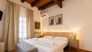 Un lit double avec deux oreillers, une table de chevet avec une lampe, un radiateur et un tableau accroché au mur.