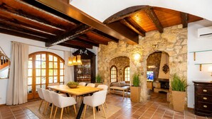 Une salle à manger spacieuse avec une table et des chaises en bois, des murs en pierre et une cheminée en pierre.