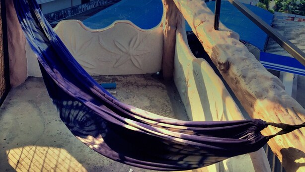 A hammock on a balcony with a view of buildings and a starry sky. - Nirvana Guesthouse (Koh Tao)