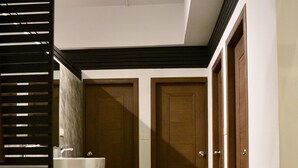 A hallway with a tiled floor, a marble sink, and a wooden door. - Nirvana Guesthouse (Koh Tao)