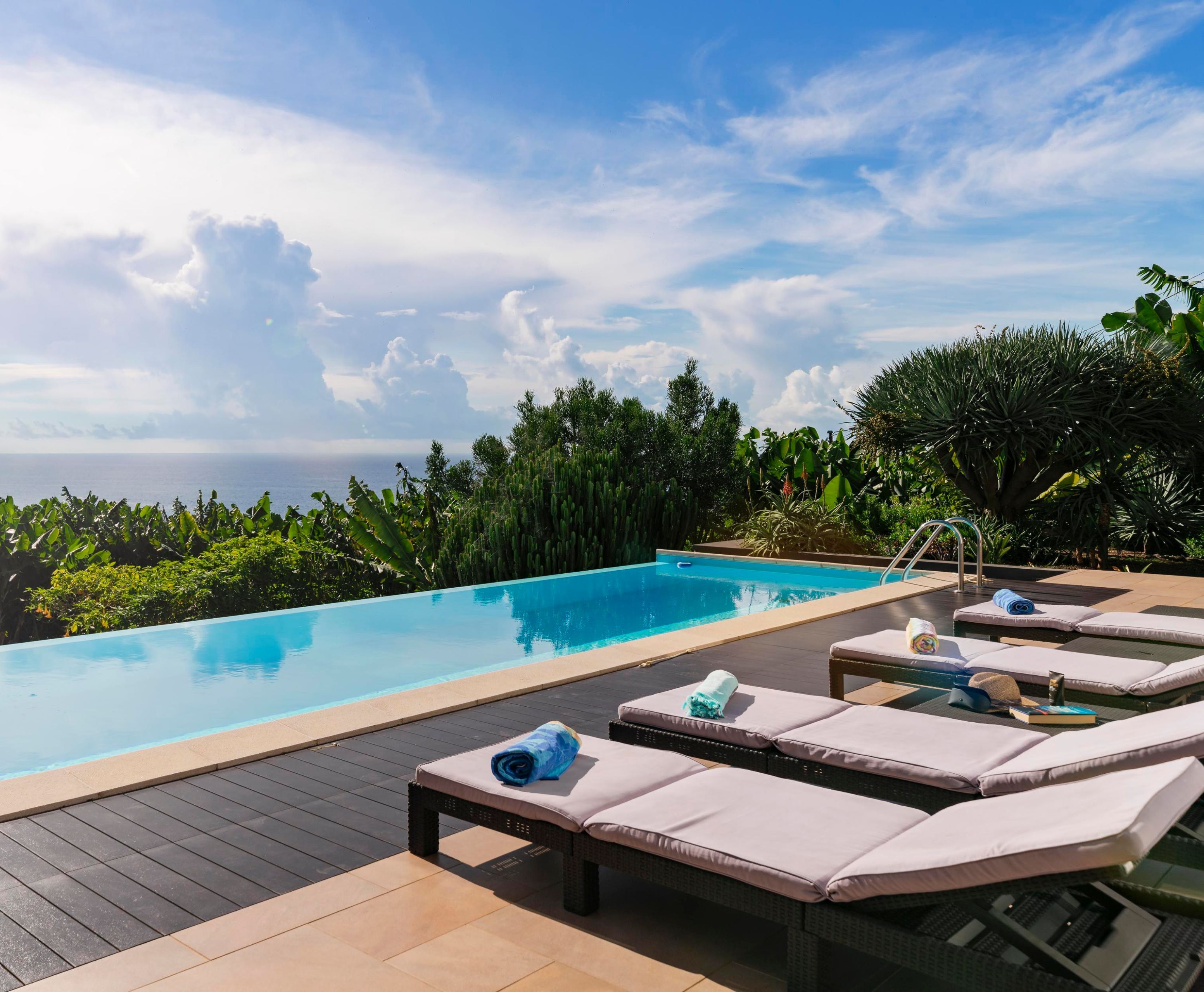 Un espace aménagé au bord de la piscine, avec des chaises longues et une vue sur l’océan.
