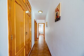 A hallway with wooden doors, a tiled floor, and a ceiling light. - Villa Casita - PlusHolidays (Calpe)
