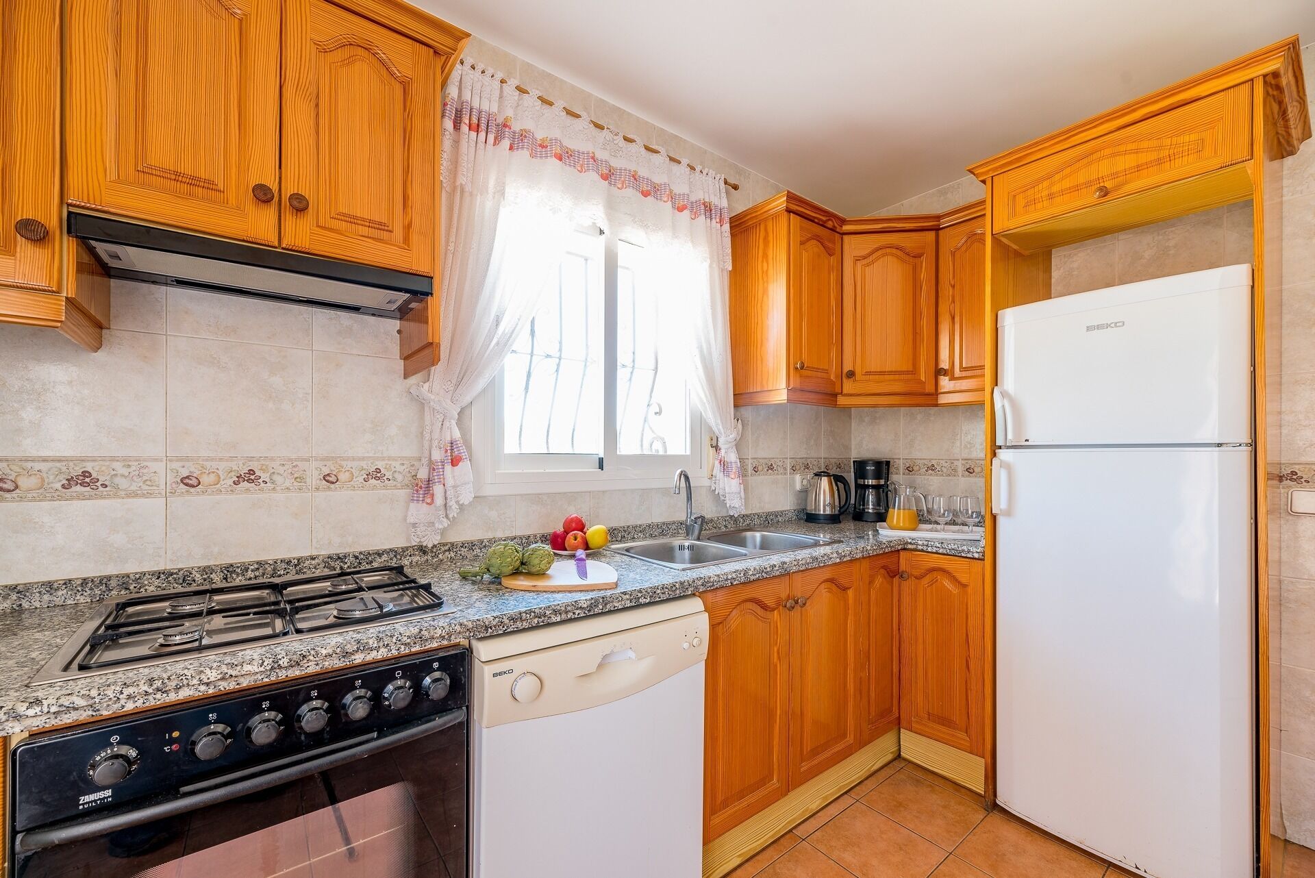 A kitchen with wooden cabinets, a white refrigerator, a stove, and a dishwasher.