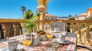 A terrace with a table set for breakfast, including cups, glasses, and a bowl of fruit. - Villa Casita - PlusHolidays (Calpe)