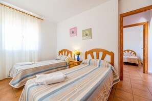 A bedroom with two beds, a nightstand, and a door leading to another room. - Villa Casita - PlusHolidays (Calpe)