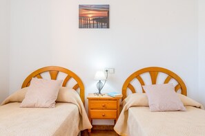 Une chambre à coucher avec deux lits en bois, une table de chevet avec une lampe et un tableau accroché au mur.
