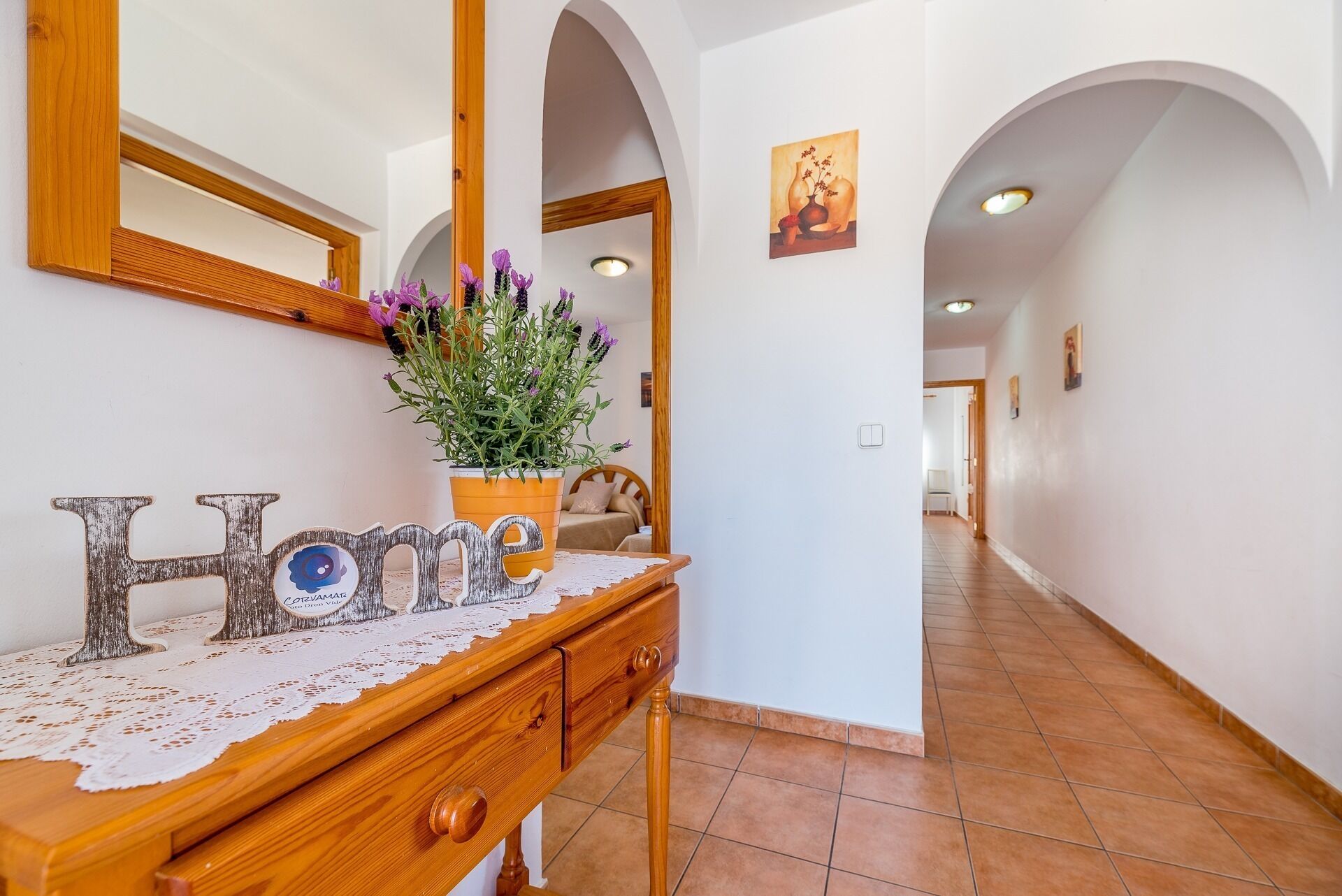 A hallway with a wooden console table, a mirror, and a potted plant.