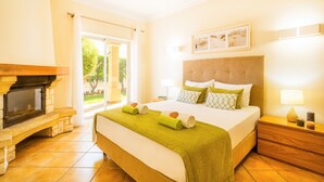 A hotel room with a bed, a fireplace, a nightstand, and a view of the outdoors. - Villa with Heatable Pool and BBQ in Albufeira (Albufeira)