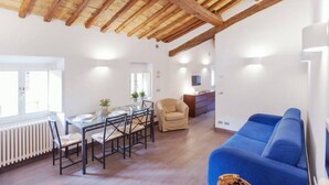 A dining area with a table and chairs, a sofa, a radiator, and a TV. - Rome, Piazza Navona, characteristic apartment for 5 people (Rome)