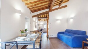 A dining area with a table set for four, a blue sofa, and a wooden ceiling. - Rome, Piazza Navona, characteristic apartment for 5 people (Rome)