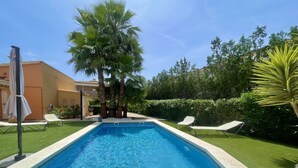 Ein rechteckiger Pool mit klarem, blauem Wasser, umgeben von einer gepflegten Rasenfläche und Palmen.