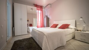 A bedroom with a bed, nightstands, a wardrobe, and a mirror.