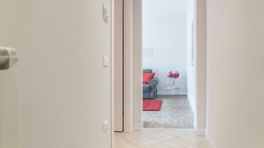 A hallway leading to a living area with a sofa, a small table, and a vase of flowers.