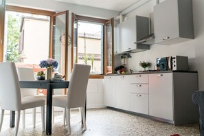 A modern kitchen with white cabinets, a built-in microwave, and a window overlooking a garden.