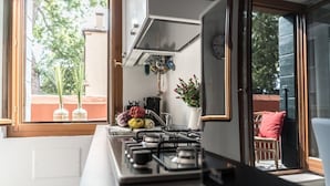 A kitchen with a gas stove, a window, and a view of the outside.