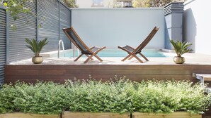 A poolside area with two lounge chairs and potted plants.