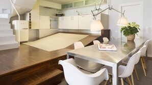 A modern kitchen with white cabinets, a wooden countertop, and a dining area with a glass table and white chairs.