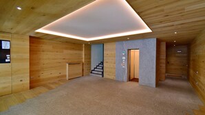 A modern interior with wooden walls, a carpeted floor, and a staircase leading to a door. - EMERALD 36 STUDIO 022143-AT-672307 (Madonna di Campiglio)