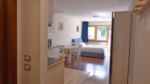 A hallway with wooden flooring leading to a bedroom with a bed and a window. - EMERALD 36 STUDIO 022143-AT-672307 (Madonna di Campiglio)