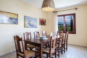 Un coin repas avec une table et des chaises en bois, un luminaire suspendu et des œuvres d’art accrochées aux murs.