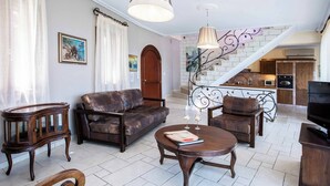 A living room with a sofa, armchairs, a coffee table, and a TV. There is a staircase leading to an upper floor. - Villa Rachi - Four Bedroom Villa, Sleeps 8 (Rachi)