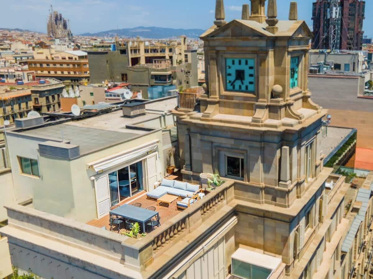 Terraza en la azotea con mobiliario exterior y una torre del reloj.