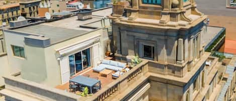 Terraza en la azotea con mobiliario exterior y una torre del reloj.