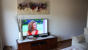 A living room with a television on a wooden stand, a white table with two bowls, and a painting above the TV. - Coster Catalanet, Villa On The Edge Off Pollença With Amazing Views ETV 1808 (Pollença)