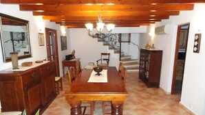 A dining area with a wooden table, chairs, and a chandelier. There is a staircase in the background leading to an upper level. - Coster Catalanet, Villa On The Edge Off Pollença With Amazing Views ETV 1808 (Pollença)
