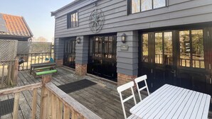 A building with a sign reading "The Granary" and a wooden deck with outdoor seating. - The Granary at Partridge Lodge (Bredfield, Woodbridge)