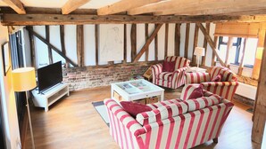 A cozy living room with striped sofas, a flat-screen TV, and a coffee table. - The Granary at Partridge Lodge (Bredfield, Woodbridge)