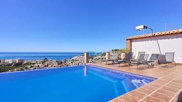 A swimming pool with a view of the sea and a cityscape.