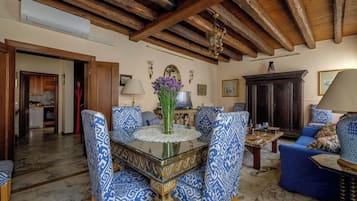 Una stanza con soffitto in legno, un tavolo da pranzo con sedie, un divano e una televisione.