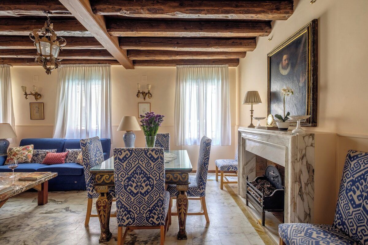 Un soggiorno con camino, arredamento blu decorato e un lampadario.