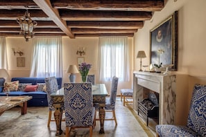 A living room with a fireplace, blue patterned furniture, and a chandelier. - Casa Dell'Albero (Venice)