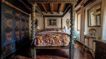 Un letto a baldacchino con elaborate decorazioni intagliate, un soffitto in legno e un quadro appeso alla parete.