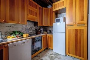 A kitchen with wooden cabinets, a white refrigerator, a stove, and a dishwasher. - Casa Dell'Albero (Venice)