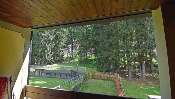 Una stanza con una grande finestra vista su una zona erbosa con alberi e un tavolo da picnic.