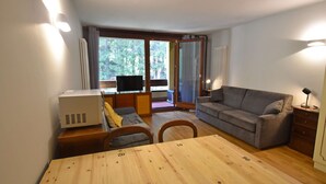 Una stanza con un tavolo da pranzo in legno, un divano grigio e una TV su un mobile.